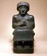 The city-state of Lagash produced a remarkable number of statues of its kings as well as Sumerian literary hymns and prayers under the rule of Gudea (c. 2150–2125 BCE) and his son Ur-Ningirsu (c. 2125–2100 BCE).<br/><br/>

This sculpture belongs to a series of diorite statues commissioned by Gudea, who devoted his energies to rebuilding the great temples of Lagash and installing statues of himself in them.<br/><br/>

Many inscribed with his name and divine dedications survive. Here, Gudea is depicted in the seated pose of a ruler before his subjects, his hands folded in a traditional gesture of prayer. The Sumerian inscription on his robe lists the various temples that he built or renovated in Lagash and names the statue: 'Gudea, the man who built the temple; may his life be long'.